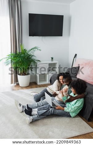 high angle view of cheerful african american family smiling and watching film on laptop at home