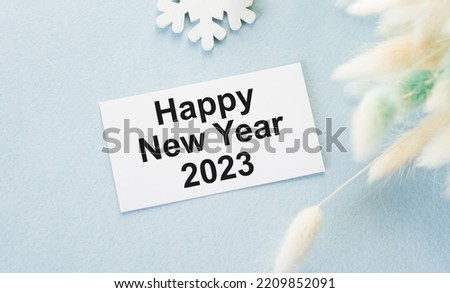 happy new year 2023 text on a card on a blue background rows of dried flower branches, holidays