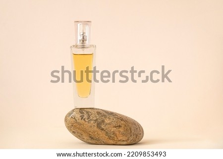 Yellow perfume bottle balancing on the striped beige color stone. Natural pastel colors.