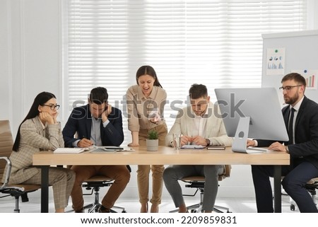 Boss screaming at employees on meeting in office. Toxic work environment Royalty-Free Stock Photo #2209859831
