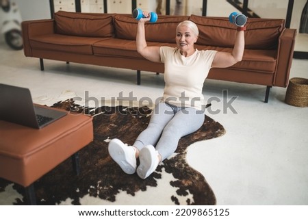 Joyful mature blonde woman doing strength workout