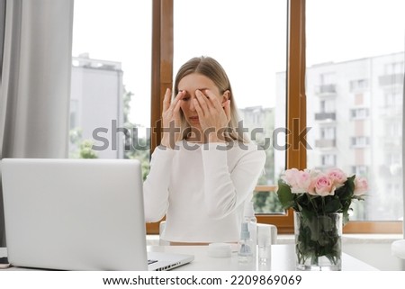 self face massage on-line course near laptop. Woman doing anti-age massage near computer. Young female doing face building facial gymnastics self massage and rejuvenating exercises
