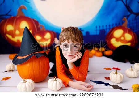 Halloween concept. Smiling kid with pumpkins on halloween spooky background.