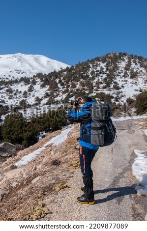 Photographer in snowy mountain area. Filming equipment. Video camera
