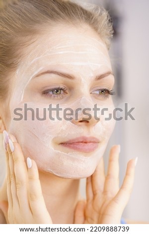 Young woman applying cream cosmetic, mask moisturizing to her face. Beauty treatment. Skincare.