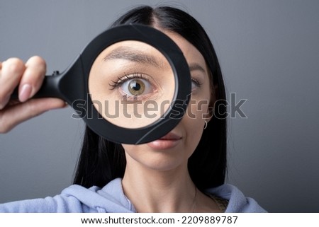 Woman looking through a magnifying glass, searching for a Finding concept . Funny humor image  Royalty-Free Stock Photo #2209889787