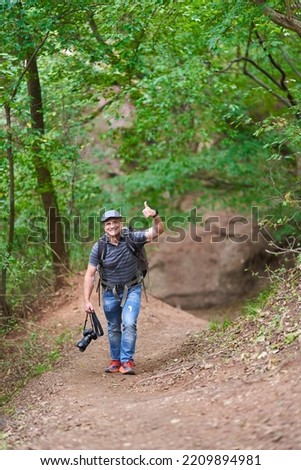 Professional travel and nature photographer hiking in the forests with large backpack and camera