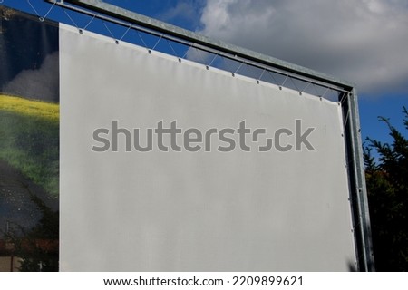 white advertising tarpaulin installed by a cable into the metal galvanized frame and shackled holes. Movable advertising solution, easily replaceable content for medium-term outdoor use company