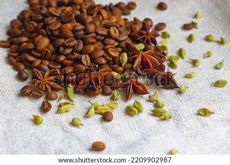 Coffee beans, cardamom and star anise on a linen tablecloth. Close-up shot with selective focus.