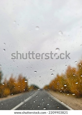 Autumn car window on the road with raindrops, copy space