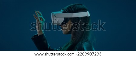 CU Portrait of Hispanic female using her VR metaverse headset against blue background