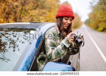 Young woman takes pictures on the camera from the car window. Tourism, rest, nature, lifestyle concept.