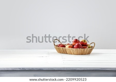 Fresh apples on white wooden table and wall with shadows. 