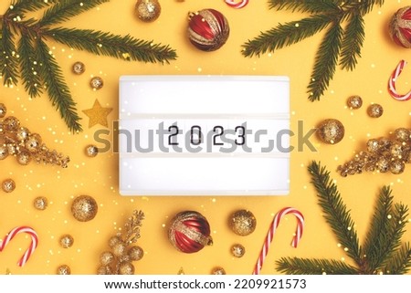 Lightbox with 2023 numbers. New Year decorations on a golden background with shiny bokeh.