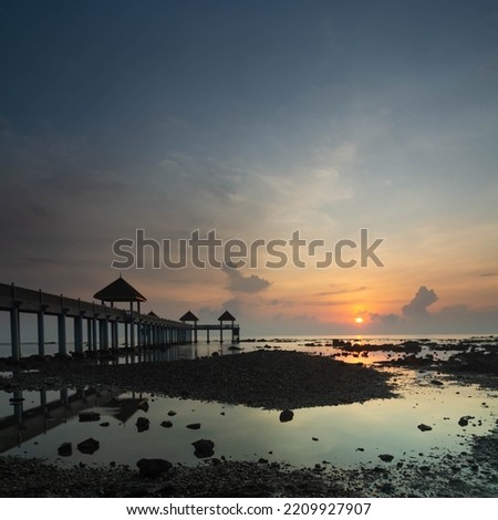 A serene view of a jetty over a beach during sunrise
