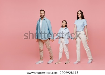 Full body young happy smiling fun parents mom dad with child kid daughter teen girl in blue clothes hold hands walk going look camera isolated on plain pastel light pink background. Family day concept Royalty-Free Stock Photo #2209928115