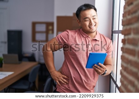 Young chinese man business worker smiling confident using touchpad at office
