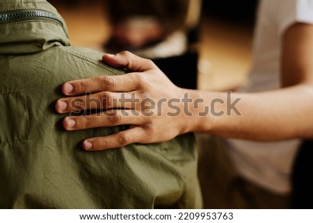 Hand of young supportive man consoling his friend or one of attendants with post traumatic syndrome caused by dramatic life event Royalty-Free Stock Photo #2209953763