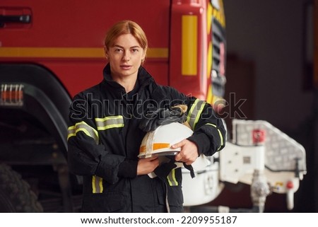 Holding helmet. Woman firefighter in uniform is at work in department.