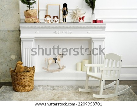 Christmas decor for a children's photo zone. A nutcracker, candles in the form of houses, a rocking horse and a natural Christmas tree stand on the fireplace. 
