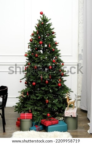 Christmas tree with gifts stands in the classic interior of the living room. Vertical photo