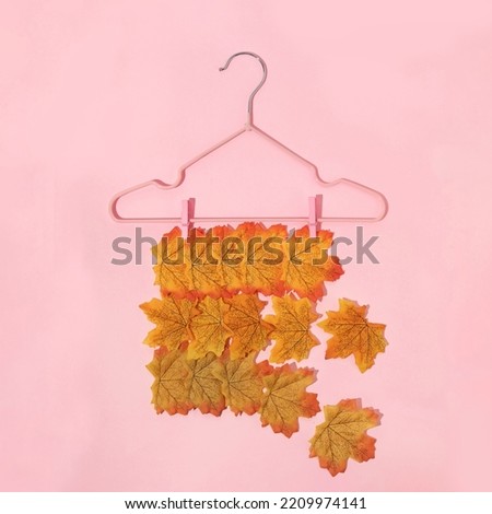 Autumn creative layout made with leaves and clothes hanger on pastel baby pink background. Vintage retro aesthetic 80s or 90s fashion concept. Minimal autumn season idea.