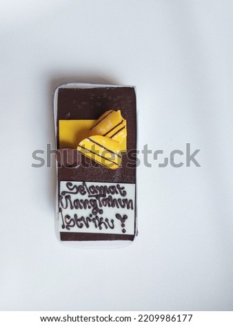 Chocolate flavored birthday cake with Indonesian text 'selamat ulang tahun istriku'.  it is means happy birthday my wife'.  isolated background in white. Flatlay photography