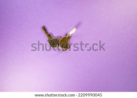 close up of a pair of silver padlock keys - one bent out of shape isolated on a purple background