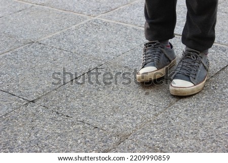 Young man wearing brand new Converse,  Converse All Stars the world’s most popular sneaker, wearing brand new black and white  Old School shoes in a grey background street , legs wearing black jeans