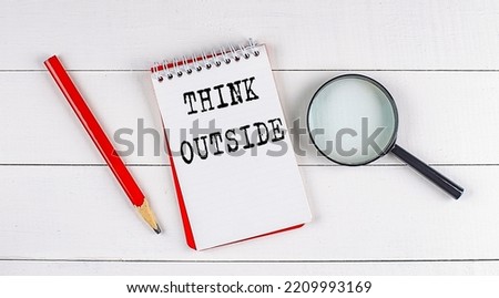 THINK OUTSIDE text on a notebook on white wooden background , business concept