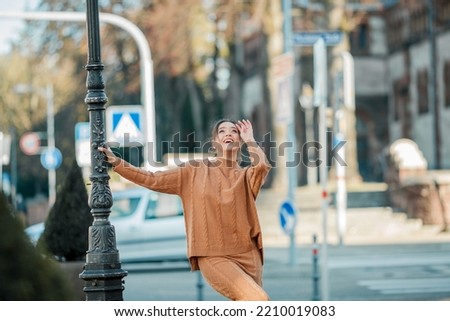 Stylish young woman in a warm suit in the city center. Beautiful model with dark long hair in autumn.