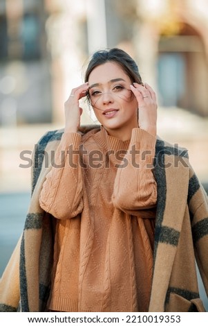 Stylish young woman in a warm suit in the city center. Beautiful model with dark long hair in autumn. Portrait.