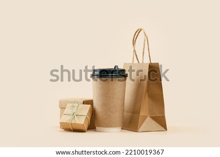 Takeaway paper coffee cup with lunch bag and bonus gift box on beige. Snack delivery service. Coffee to go. Grab and go or carry out beverage. Disposable mockup packaging. Place for text. Minimal Royalty-Free Stock Photo #2210019367