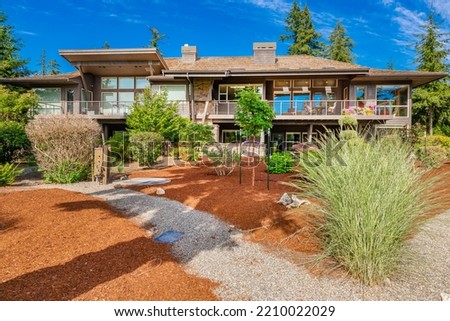 modern contemporary home with cedar paneling flat roof picture windows blue sky and lush green landscaping 