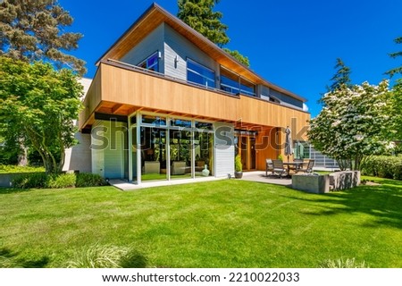 modern contemporary home with cedar paneling flat roof picture windows blue sky and lush green landscaping 