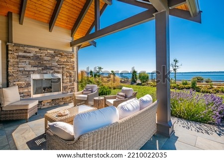 Bright sunny patio decks with furnishings fireplace BBQ and beautiful views of ocean and golf course Royalty-Free Stock Photo #2210022035