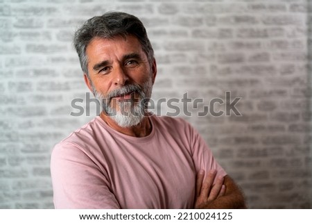 Smiling successful confident mature bearded casual business man wearing pink t-shirt holding hands crossed isolated on grey color background studio portrait. Achievement career wealth concept Royalty-Free Stock Photo #2210024125