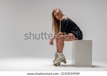 beautiful seated woman wearing skates looking at camera, young woman with skates on her feet looking at camera
