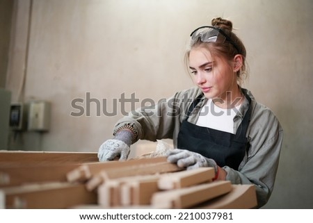 Young beautiful woman doing work in the carpenter DIY workshop room. Small Business owner, young woman who working at furniture factory. Royalty-Free Stock Photo #2210037981