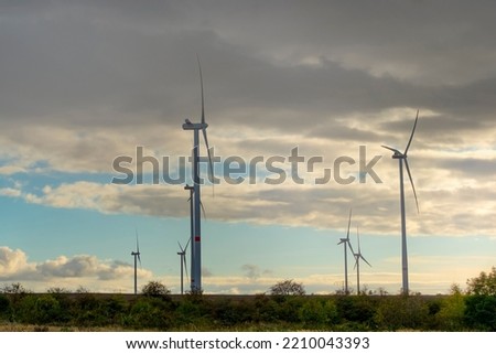 Wind turbines generate green energy in a field at sunset.