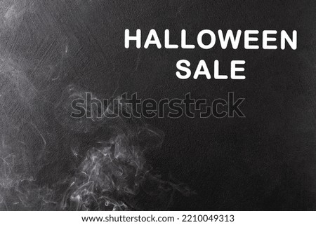 White smoke on the left on a black background rises up. On it is the inscription Halloween Sale in white letters