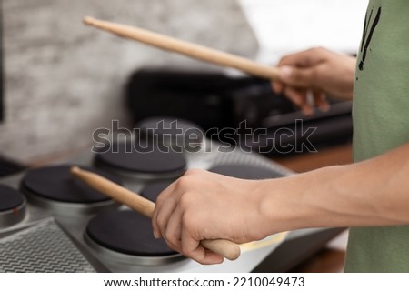 Hands of a young musician playing electronic drums with sticks, close-up, selective focus Royalty-Free Stock Photo #2210049473