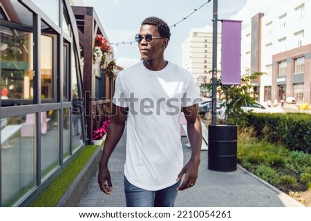African american man in a white t-shirt walking down the street. Mock-up.