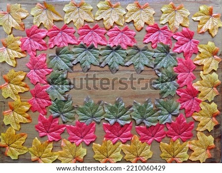 Multicolored autumn artificial leaves lie on a wooden background for copyspace