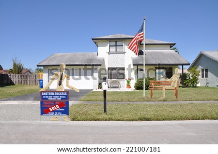 Mannequin holding sold another success let us help you buy sell your next home real estate sign on driveway Manikin sitting reading paper of suburban home residential neighborhood USA clear blue sky