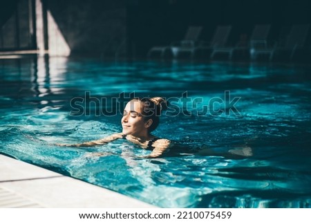 Woman relaxing in the swimming pool. Royalty-Free Stock Photo #2210075459