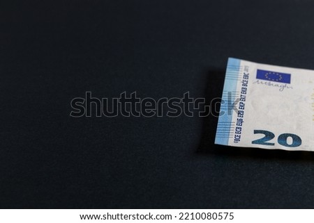 Black background with a 20 euro banknote on the edge of the image. Black background with banknote and free space for text, copy space.