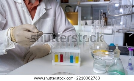 Scientist working with laboratory samples of nutritional supplements and making notes in a notebook