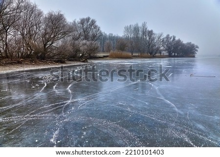 Frozen lake surface in cold winter landscape Royalty-Free Stock Photo #2210101403