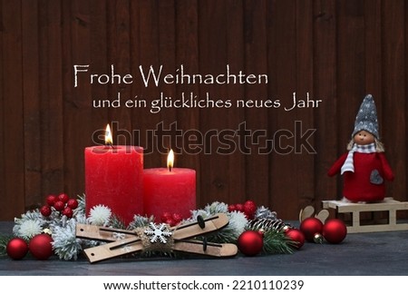 Rustic decoration with red Christmas candles, branches and Christmas balls and the German text Frohe Weihnachten und ein
glückliches neues Jahr, means translated Merry Christmas and Happy New Year.